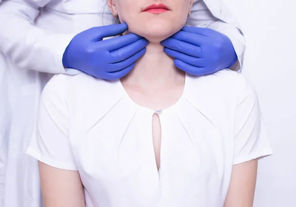 Doctor specialist diagnoses palpation on the throat of the caucasian girl for the presence of enlarged lymph nodes and tumors, adenoids — Stock Photo, Image