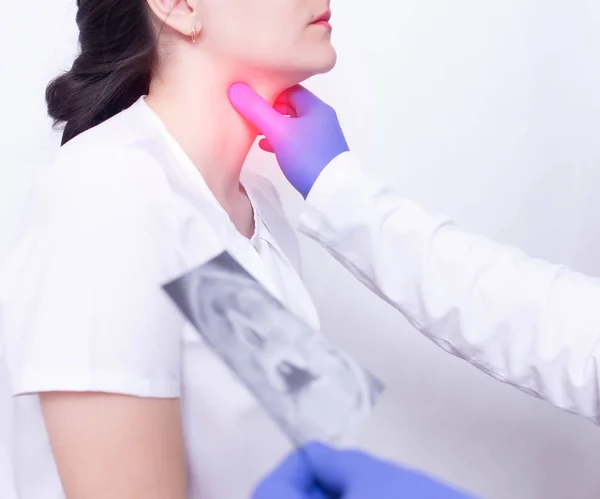 Um médico especialista diagnostica a dor de garganta de uma menina, palpando a presença de inflamação e inchaço, dor de garganta e amigdalite da garganta — Fotografia de Stock