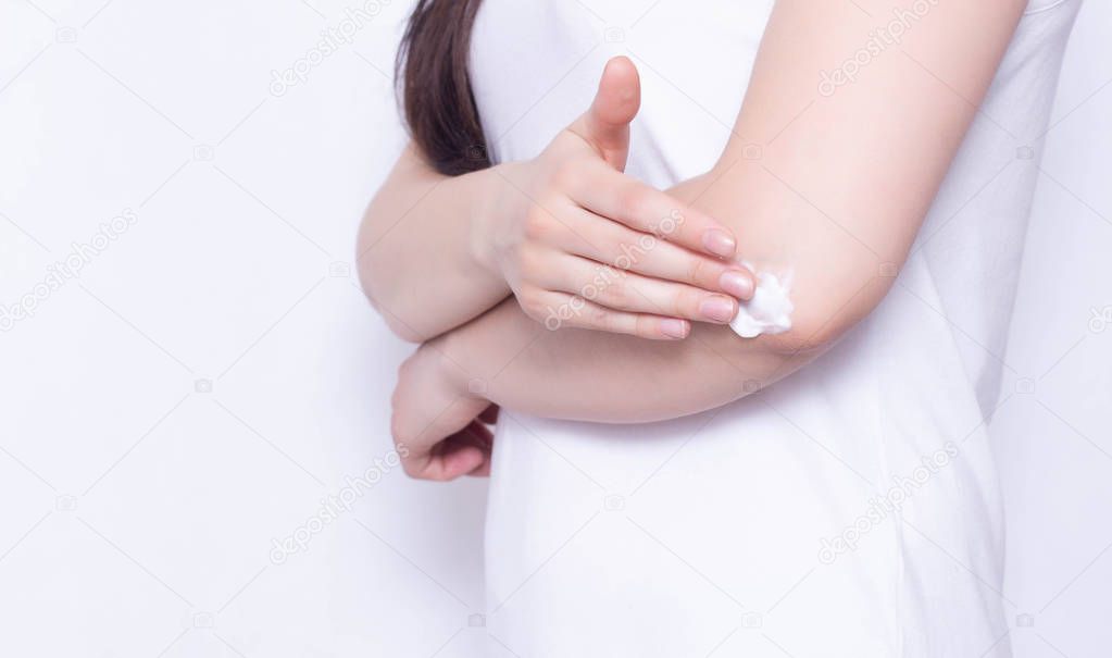 The girl rubs the healing cream and balm in the elbow joint to relieve pain and inflammation, white background, copy space, anti-inflammatory