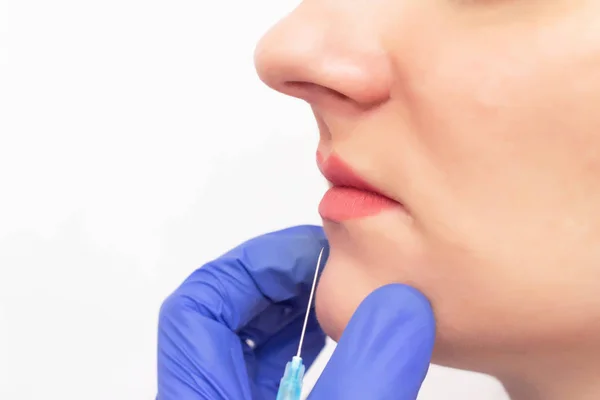 Médico cosmetologista realiza procedimento de aumento de lábios de menina branca jovem usando uma cânula, agulhas, aumento de lábios, espaço de cópia — Fotografia de Stock