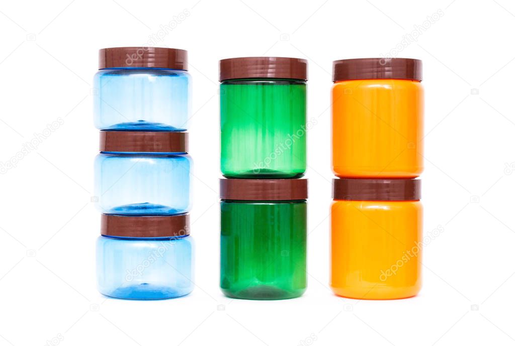 Multicolored plastic jars of orange, green and blue on a white background, polypropylene