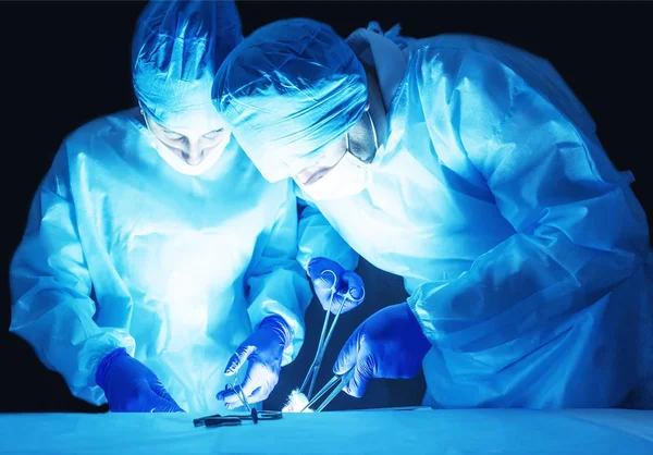 Dos cirujanos, un hombre y una mujer, realizan una cirugía para extirpar el adenoma de próstata y el varicocele, fibroadenoma — Foto de Stock