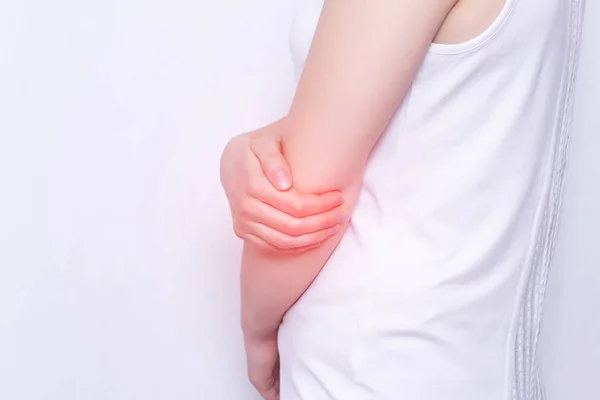 Young girl holding her elbow joint, pain and inflammation in the elbow, white background, close-up, medical, copy space — Stock Photo, Image