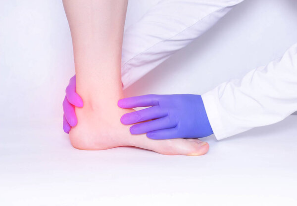 Врач проводит медицинское обследование голеностопного сустава пациента для выявления артрита и синовитов, травм, люксов
