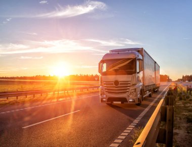 Modern wagon truck transports cargo against the backdrop of a sunset. The concept of truck drivers in the field of freight and logistics, copy space clipart