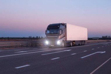 A black modern truck wagon transports cargo in a trailer refrigerator at night. Concept logistics and online stock exchange for the selection of goods and freight, copy space clipart