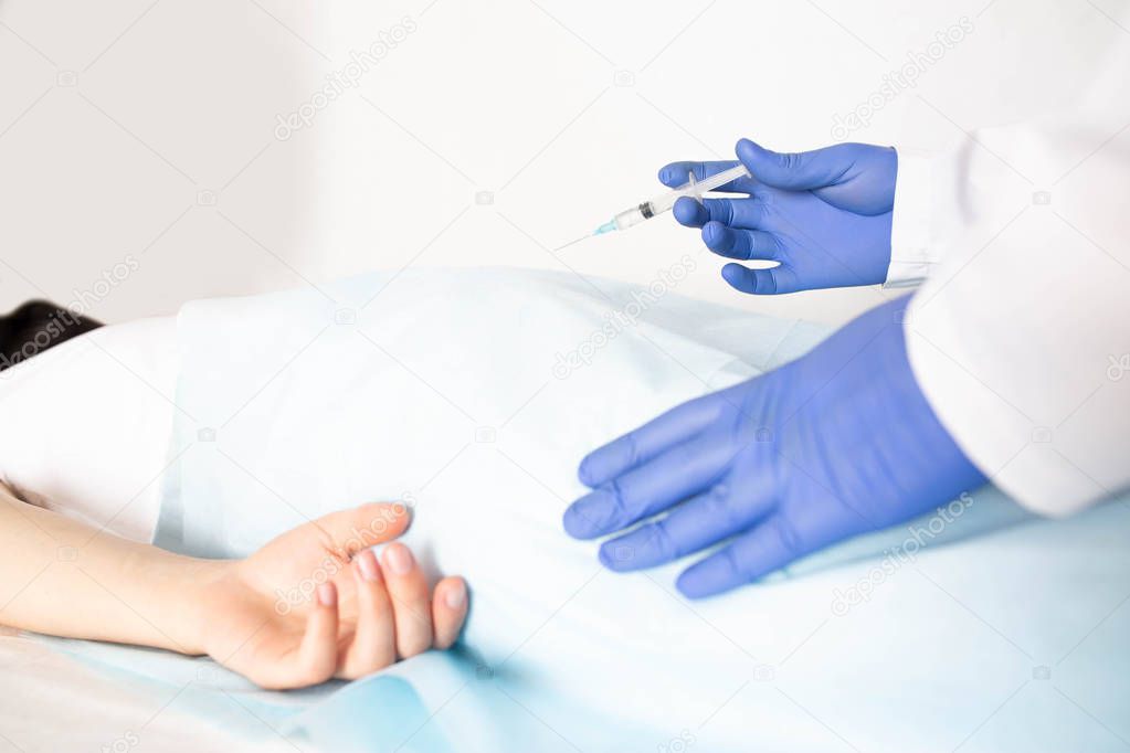 Doctor proctologist treats a patient for hemorrhoids with the help of modern method sclerotherapy, white background, copy space, painlessness