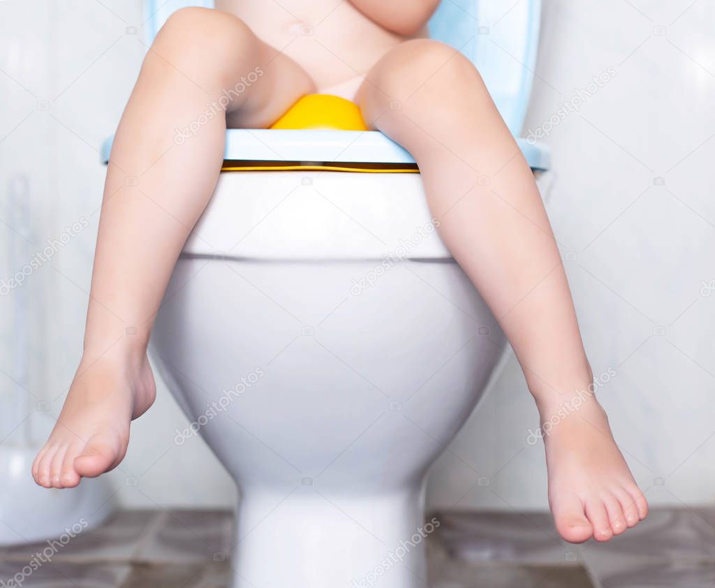 A small child is sitting in the toilet on the toilet, the concept of teaching the child to the toilet and the problems of digestion in children