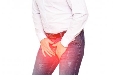 A man in a white shirt holds on to his groin, the concept of pain and inflammation in the groin, genital infections in men and prostatitis. White background, isolate clipart