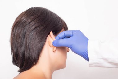 Bir plastik cerrah doktor bir otoplasti ameliyatı yapmadan önce bir hastanın kız kulakları inceler, yakın çekim
