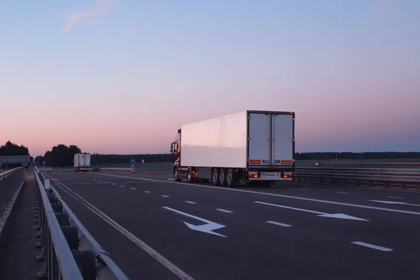 Un convoy de camiones camiones transporta la carga por la noche en la carretera, el concepto de logística y carga, espacio de copia —  Fotos de Stock