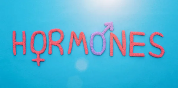 The word hormones from red plasticine on a blue background concept of all human hormones, inscription — Stock Photo, Image