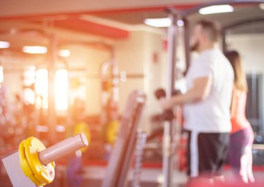 Bir adam ve bir kız güneşli gün batımı, bulanık, arka plan fonunda modern bir spor salonunda meşgul