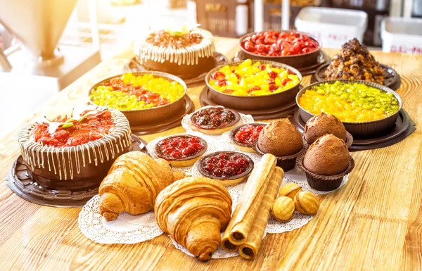 Натюрморт сладких и вкусных продуктов из тортов, кексов и круассанов на столе, фон — стоковое фото