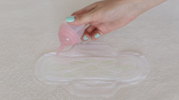 A girl pours water on a menstrual sanitary pad. Leakage protection concept, close-up — Stock Video