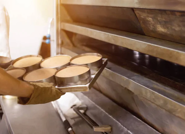 Ένας άντρας μάγειρας βγάζει ψωμί από ένα ζεστό φούρνο σε ένα αρτοποιείο, βιομηχανία — Φωτογραφία Αρχείου