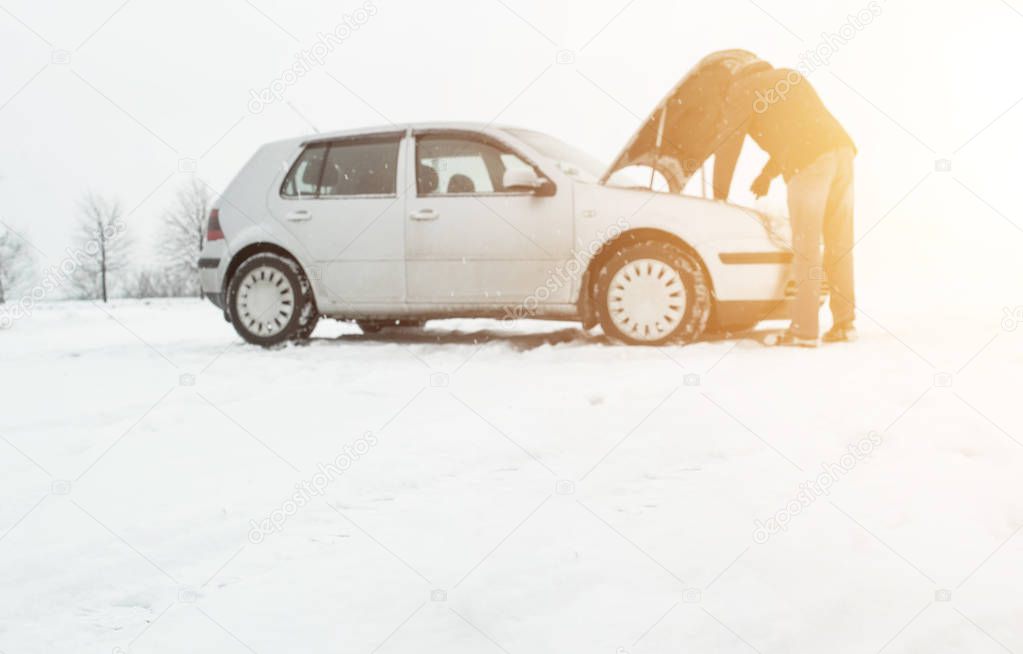A man stands by a car with an open hood in the winter. The concept of freezing diesel fuel in a diesel system, low-quality fuel, copy space