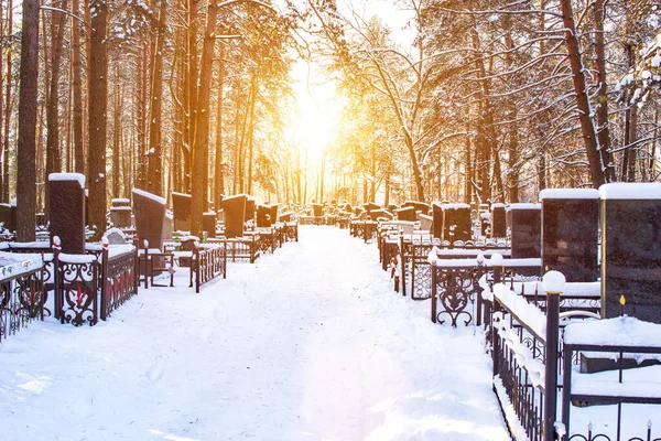 Zimowy cmentarz w tle słońca, alejka. Przestrzeń kopiowania — Zdjęcie stockowe