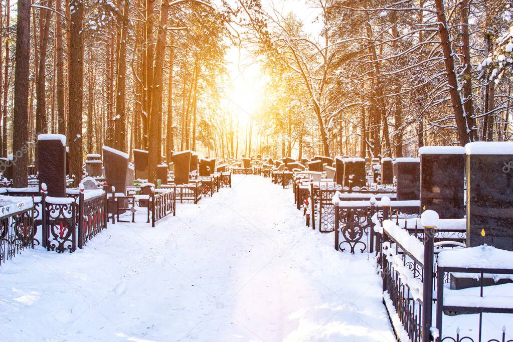 Winter cemetery in the background of the sun, alley. Copy space