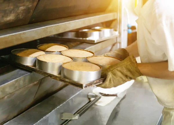 Αρσενικό μάγειρα παίρνει κέικ από ένα ζεστό φούρνο για την κατασκευή κέικ, βιομηχανία — Φωτογραφία Αρχείου