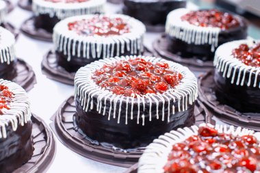 Taze kiraz ve kremalı bir sürü güzel ve lezzetli çikolatalı kek. Pasta ve pasta imalatı için şekerleme üretimi, turta