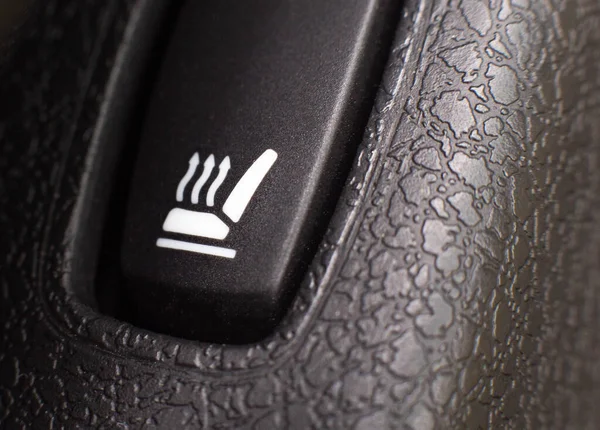 Seat heating power button, closeup. Modern switch in the car, background