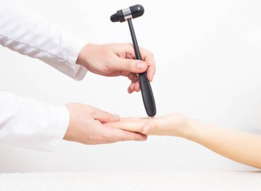 Bir nörolog, bir kızın avuç içi çene refleksini nörolojik çekiçle inceler. Cervicocranialgia