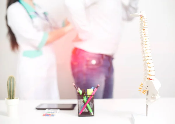 Doktor bir omurgacıyla randevuda olan erkek hasta. Sırt ağrısı hastalıklarının teşhisi ve tedavisi, geçmiş. Omurgalar arası diskin yerinden çıkması ve travması, sinir sıkışması, omurilik bozuklukları.