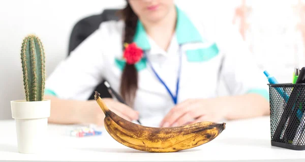 Schwarze Banane im Vordergrund im Büro eines Arztes eines Sexualtherapeuten. Das Konzept des Problems bei Männern ist eine Schwächung der erektilen Dysfunktion, eine schwache Erektion, ein Problem mit der Potenz und — Stockfoto