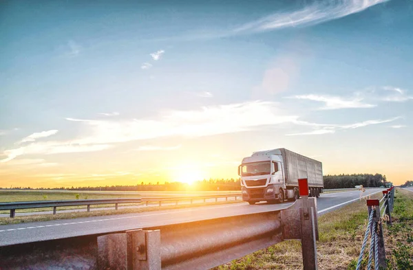 在日落的背景下，一辆倾斜的欧元卡车在高速公路上运载货物。在公路、安全、国际运输等方面中途停留 — 图库照片
