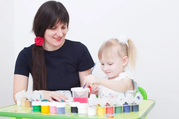 Young caucasian beautiful mother draws with her little daughter, preparing for school, copy space — ストック写真