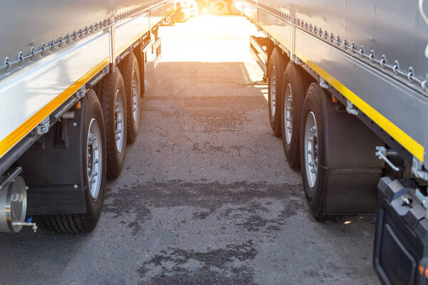 Two new truck semi-trailers are parked in a truck stop. Cargo transportation concept axle load, overload, copy space for text