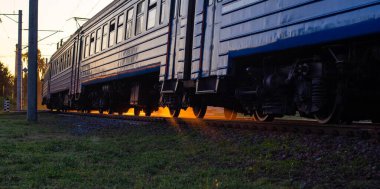 Yolcu treni, güneşli bir gün batımının arka planında, akşam saatinde. Demiryolu yolcu taşıma konsepti, metin ve turizm için kopyalama alanı