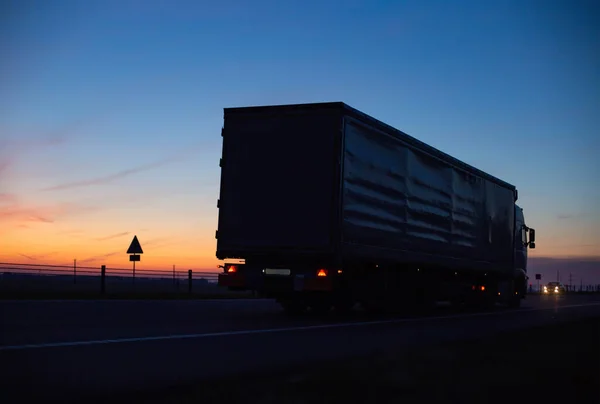 a cargo truck drives on the motorway in the evening against the backdrop of sunset. Truck logistics and transportation concept, copy space for text, shipping