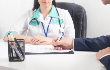 Bir adam cinsiyet değiştirme ameliyatına rıza gösteren belgeleri imzalıyor. Modern bir klinikte cinsiyet değişimi, kadınlaşma