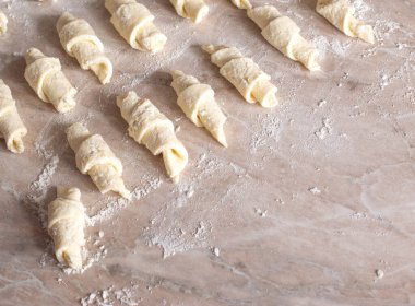 Masanın üzerinde hamurdan yapılmış ev yapımı süzme peynirli simit ve süzme peynir var. Lezzetli hamur işleri