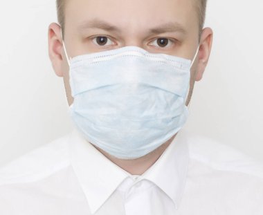 Beyaz arka planda koruyucu tıbbi maskeli genç beyaz adam, ikinci dalga koronavirüs ve pandemik konsept, portre