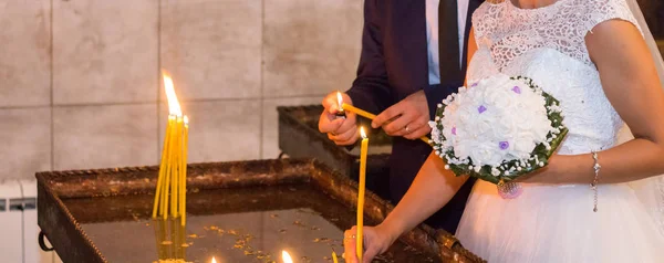 The bride and groom put candles in the church