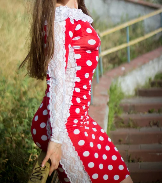 Girl in a red polka-dot dress walks in the park