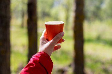 Kırmızı kağıt bardak, arka planda sıcak içecekler için.