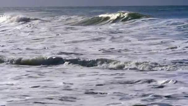 Vagues se brisant près du rivage, avec le soleil brille sur eux 