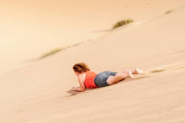 Sossusvlei, Namibya - 6 Ocak 2016: Namib-Naukluft Milli Parkı, Namibya'da kimliği belirsiz kız kumuldan aşağı kayıyor. Bir park Namib Çölü'nün bir parçasıdır, en eski çöl