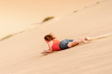 Sossusvlei, Namibya - 6 Ocak 2016: Namib-Naukluft Milli Parkı, Namibya'da kimliği belirsiz kız kumuldan aşağı kayıyor. Bir park Namib Çölü'nün bir parçasıdır, en eski çöl