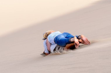 Sossusvlei, Namibya - 6 Ocak 2016: Namibya'daki Namib-Naukluft Milli Parkı'nda ahşap bir kalıbın üzerinde kumuldan aşağı kayıyor. Milli park, En eski çöl olan Namib Çölü'nün bir parçasıdır.