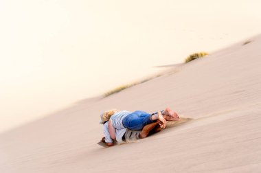 Sossusvlei, Namibya - 6 Ocak 2016: Namibya'daki Namib-Naukluft Milli Parkı'nda ahşap bir kalıbın üzerinde kumuldan aşağı kayıyor. Milli park, En eski çöl olan Namib Çölü'nün bir parçasıdır.