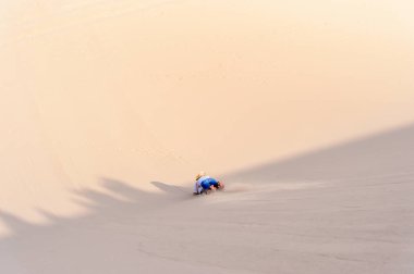 Sossusvlei, Namibya - 6 Ocak 2016: Namibya'daki Namib-Naukluft Milli Parkı'nda ahşap bir kalıbın üzerinde kumuldan aşağı kayıyor. Milli park, En eski çöl olan Namib Çölü'nün bir parçasıdır.