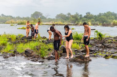 Livingstone Adası, Zambiya - 14 Ocak 2016: Kimliği belirsiz turistler, İskoç kaşif David Livingstone'un adını taşıyan Livingstone Adası'ndaki Zambezi nehrinde yüzmek üzere,