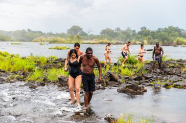 Livingstone Adası, Zambiya - 14 Ocak 2016: Kimliği belirsiz turistler, İskoç kaşif David Livingstone'un adını taşıyan Livingstone Adası'ndaki Zambezi nehrinde yüzmek üzere,