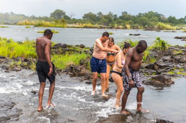 Livingstone Adası, Zambiya - 14 Ocak 2016: Kimliği belirsiz turistler, İskoç kaşif David Livingstone'un adını taşıyan Livingstone Adası'ndaki Zambezi nehrinde yüzmek üzere,