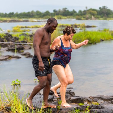 Livingstone Adası, Zambiya - 14 Ocak 2016: Kimliği belirsiz turistler, İskoç kaşif David Livingstone'un adını taşıyan Livingstone Adası'ndaki Zambezi nehrinde yüzmek üzere,